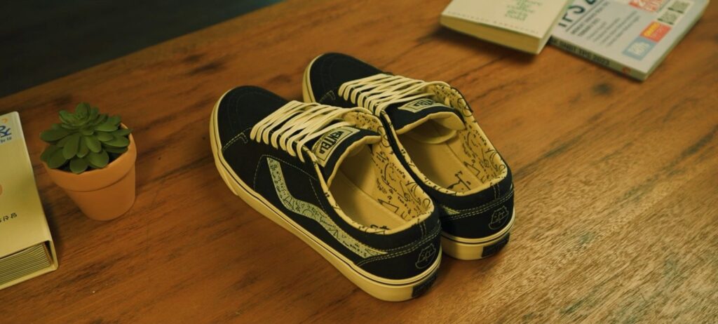 Sepasang sepatu Ventela x Jerome Polin navy dengan insole bergambar di atas meja kayu