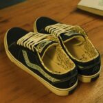 Sepasang sepatu Ventela x Jerome Polin navy dengan insole bergambar di atas meja kayu